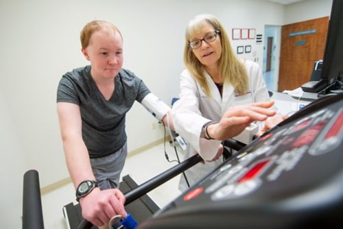 A patient on a treadmill with a care team member