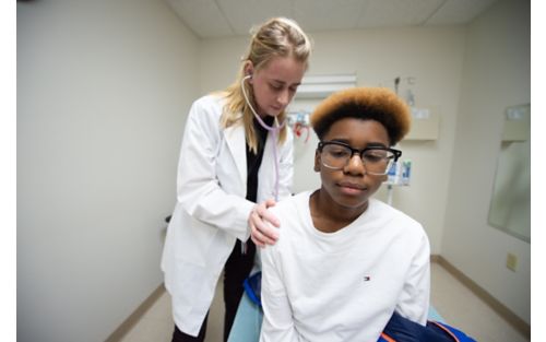 Male child patient being evaluated by female doctor with stethoscope