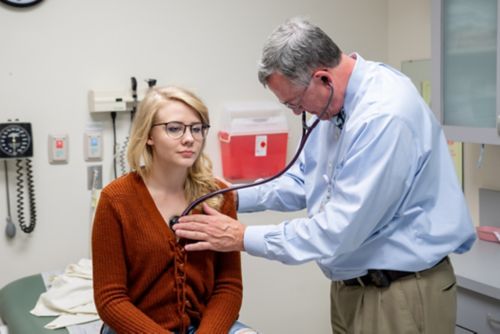 Cardiac late effects in childhood cancer survivors occur due to certain treatments. Anthracycline medicines and chest radiation may lead to heart disease in some childhood cancer survivors. In this image, a physician listens to a childhood cancer survivor’s heart during a check-up.