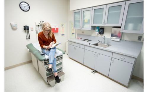 Female teen patient sitting in hospital room waiting to be seen by medical professional