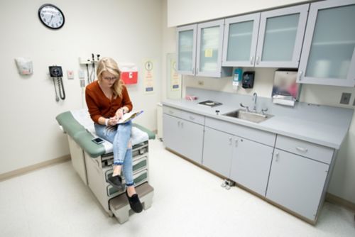 A survivorship care plan is a concise, complete record of a patient’s treatment, specific medical concerns, and recommended health screenings – all in one document. In this image, a childhood cancer survivor waits in a clinic room during a follow-up visit. 