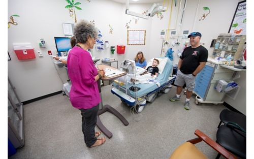 Male child patient in hospital room with family and staff