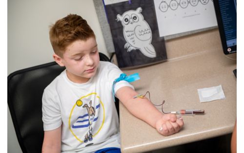 Male child holding arm out for blood draw