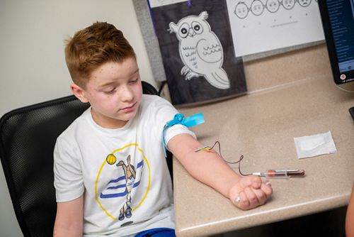 Niño sentado con un brazo del que se le extrae sangre