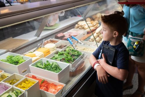 Os sobreviventes de câncer que desenvolvem hábitos alimentares saudáveis podem reduzir o risco de obesidade, além de reduzir o risco de alguns tipos de cânceres na vida adulta. Paciente jovem analisa opções de comida em uma vitrine expositora