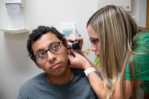 Um pesquisador em audiologia examina um paciente com câncer pediátrico.