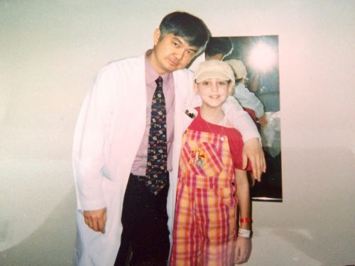 Patient wearing a hat standing next to doctor in a white coat.
