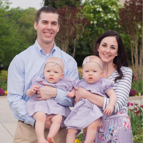 Patient as an adult, standing with her husband. Each of them is holding one of their twin children.