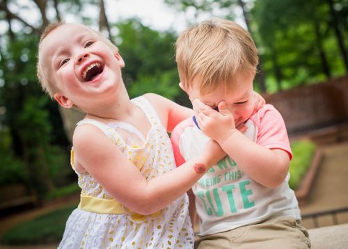 Young pediatric cancer patient plays with her brother outside