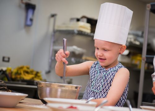 Pediatric cancer patient stirs a bowl of pancake batter.
