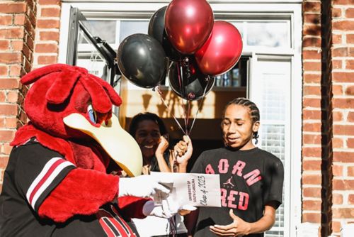 MJ reçoit sa lettre d'admission à l'Université de Caroline du Sud des mains de la mascotte costumée de l'université.