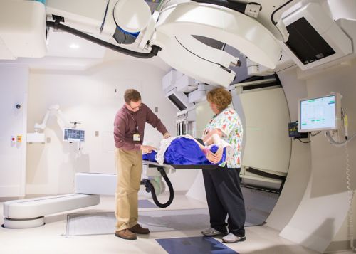 Two radiation therapists preparing a pediatric cancer patient for a radiation treatment.