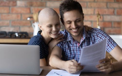 Cancer patient and husband smile while looking at papers