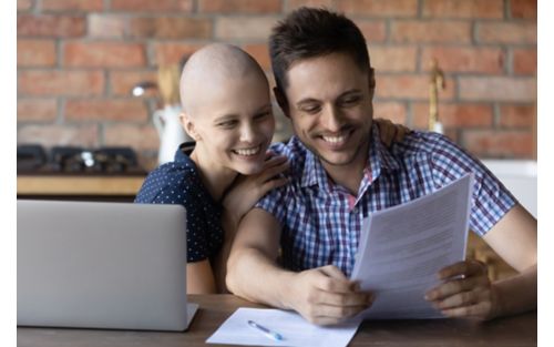 Cancer patient and husband smile while looking at papers