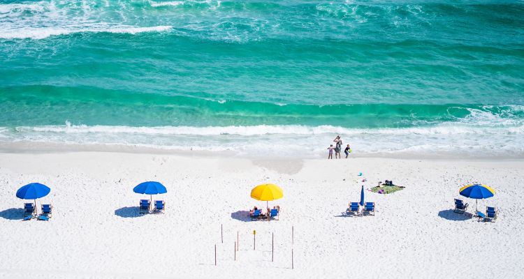 White sandy beach with aqua blue ocean, colorful beach umbrellas