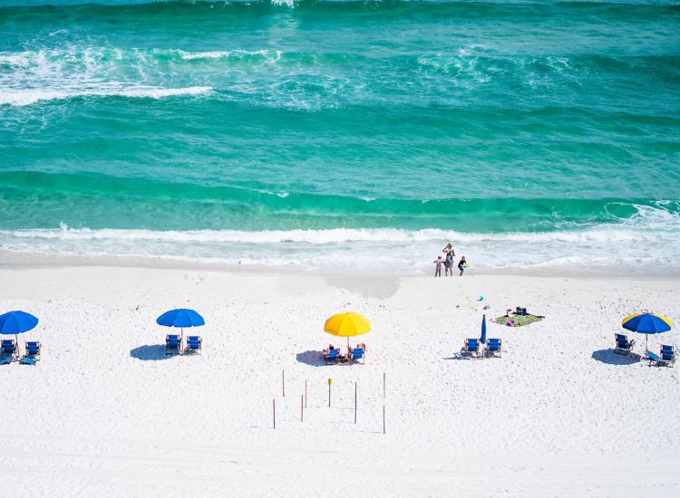 White sandy beach with aqua blue ocean, colorful beach umbrellas