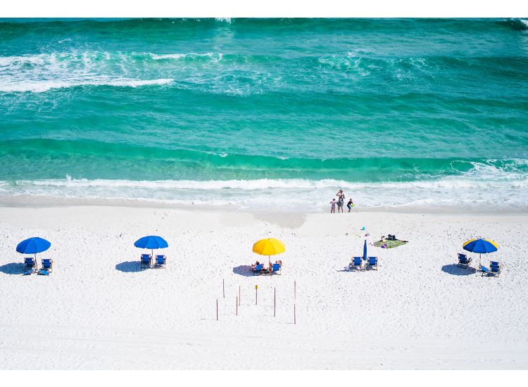 White sandy beach with aqua blue ocean, colorful beach umbrellas