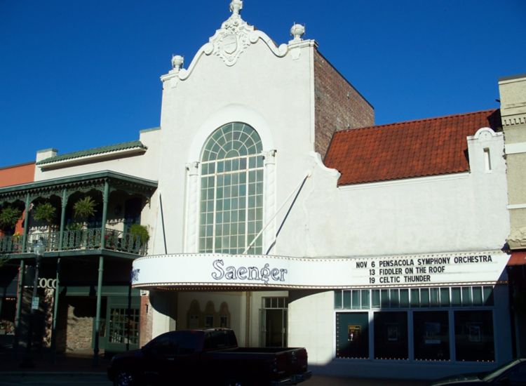 Exterior of Pensacola Saenger Theater, marquis with show dates, white building with red accents