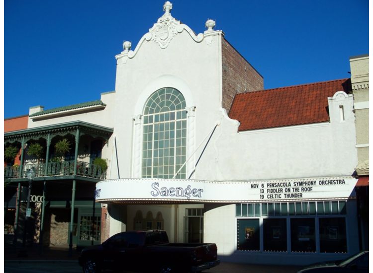 Exterior of Pensacola Saenger Theater, marquis with show dates, white building with red accents