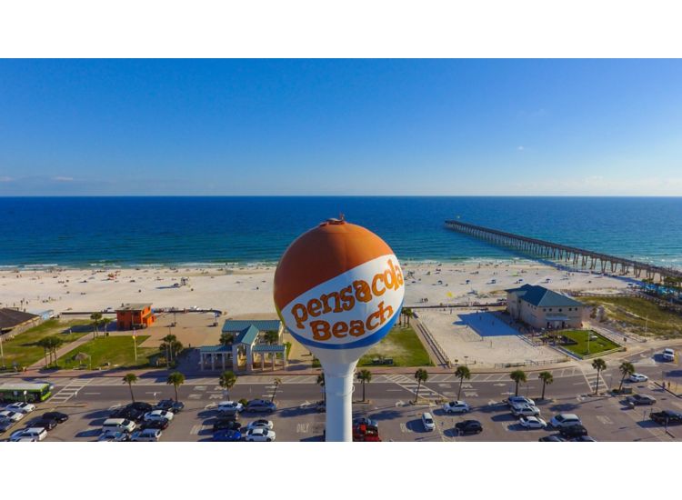 Pensacola Beach Florida water tower in front of sandy beach, blue ocean and boardwalk