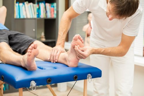 Un médico que prueba la sensibilidad del pie de un paciente. Esta prueba se suele usar para verificar la neuropatía.