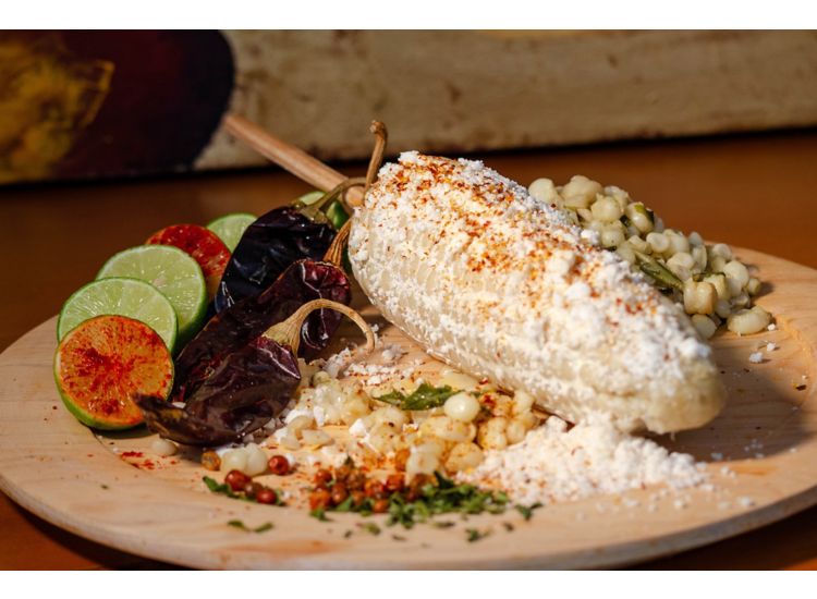 Plated Mexican street corn with lime wedges.