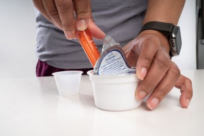 Putting medicine into cup with syringe.