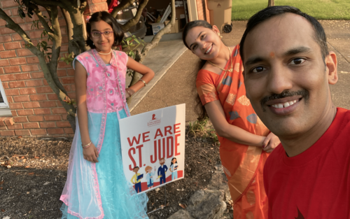 Selfie-stye photo of man and wife and childm, who are dressed in traditional Indian garb.