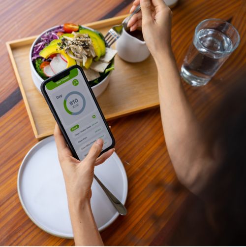 image of someone's hands eating a salad and holding a smart phone