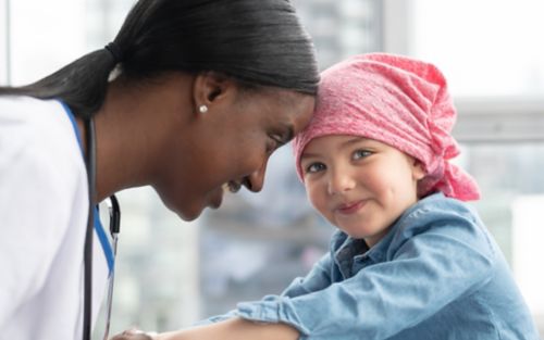 Female doctor smiles at female child cancer patient