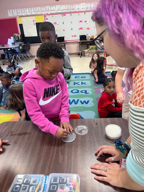 Teacher showing kindergarten student how to swab an agar plate