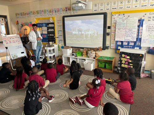 man in white coat in classroom full of kindergarteners