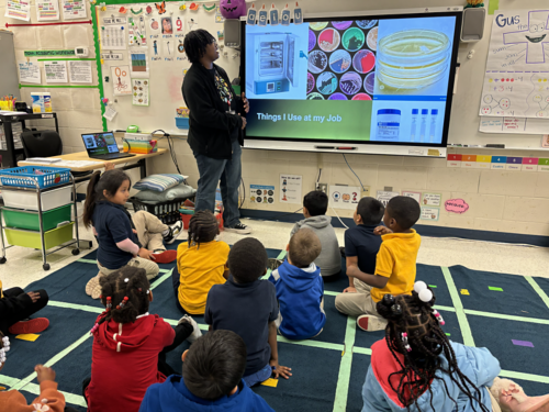 Teacher showing kindergarten students something on big screen