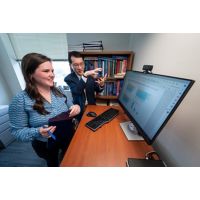 man and woman standing before computer monitor