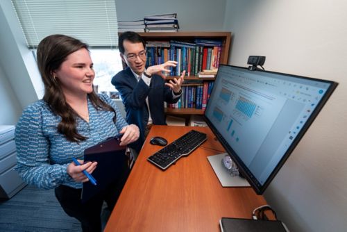 Man and woman discussing something in front of a computer monitor