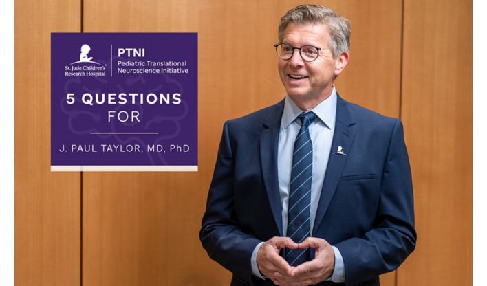 Paul Taylor standing in front of a wood-paneled wall