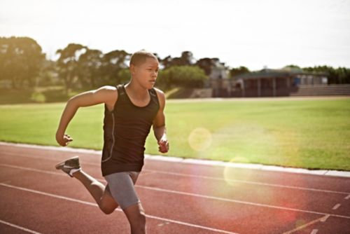 Young man running on track field