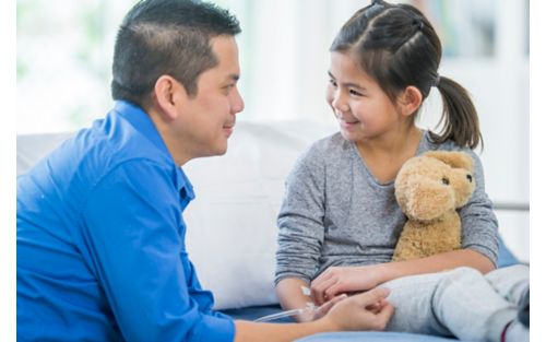 Father smiling at daughter holding stuffed animal