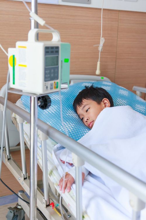 मॉनिटर के साथ अस्पताल के बिस्तर पर छोटा लड़का