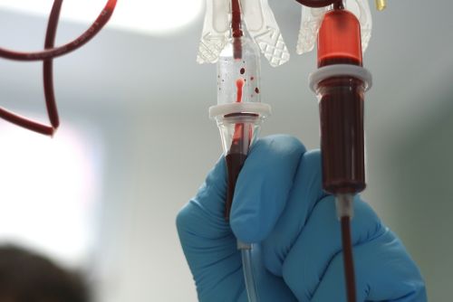 A gloved hand connecting a blood transfusion