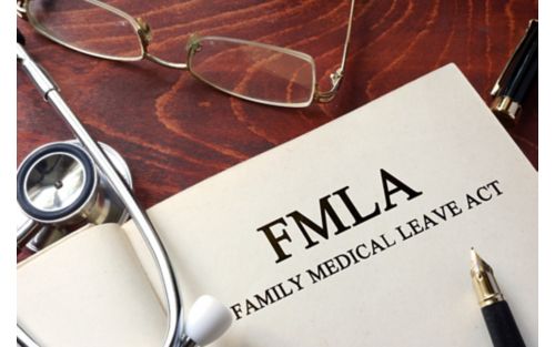 An open book on a table next to a stethoscope and a pair of glasses. The book says FMLA Family Medical Leave Act.