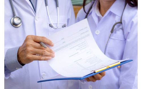 Two doctors in white coats, one holding clipboard 