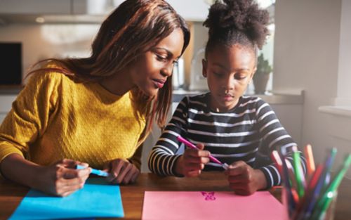 A mother and daughter working on craft projects.