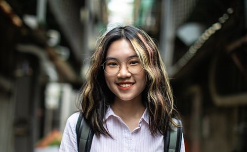 A portrait of a teenage girl smiling while wearing glasses.