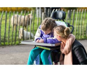 Social worker helps girl in wheelchair.