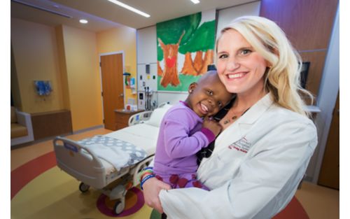 Female researcher holding child in hospital room