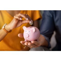 stock photo of woman putting a coin in piggy bank