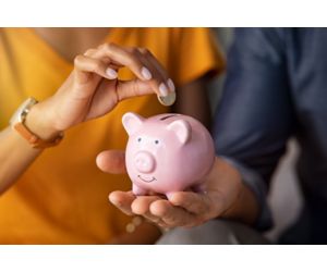 stock photo of woman putting a coin in piggy bank