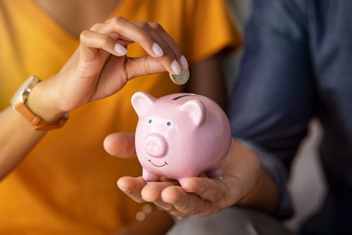 fotografía de archivo de una mujer que introduce una moneda en una alcancía con forma de cerdito