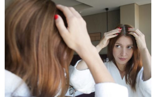 Woman looking at scalp in a mirror